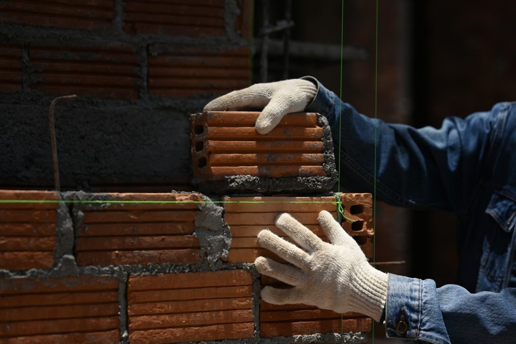 Close up of bricklayer installing bricks on construction site.