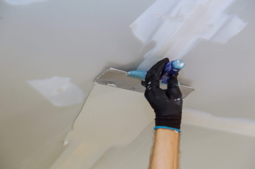 Closeup of a man aligning a wall with spatula and plastering gypsum cardboard wall