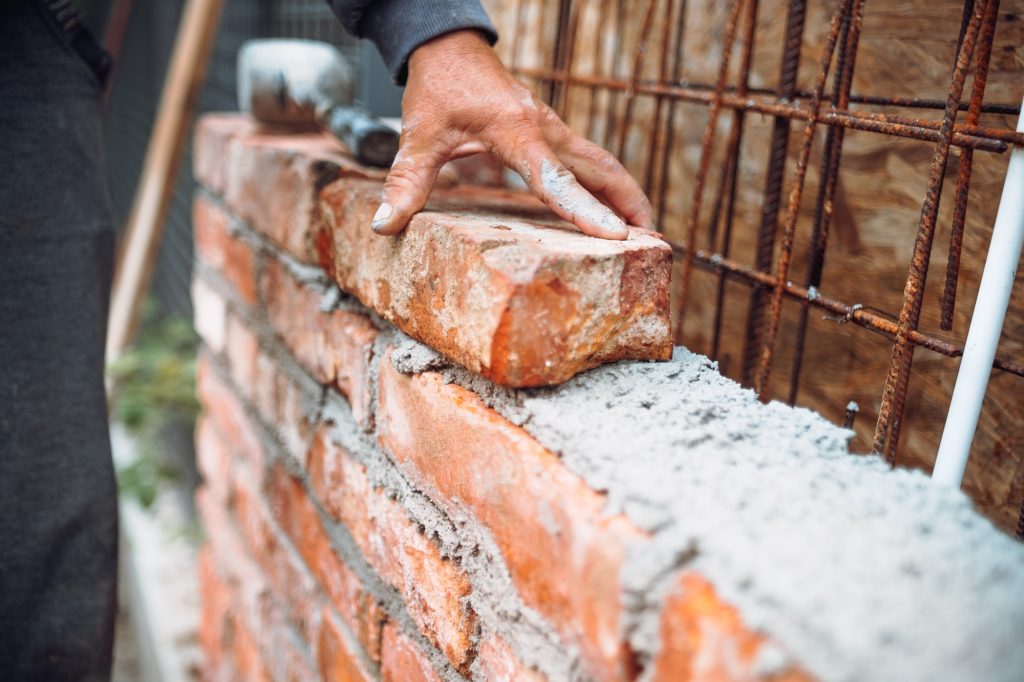 construction worker laying bricks and building walls on industrial construction site